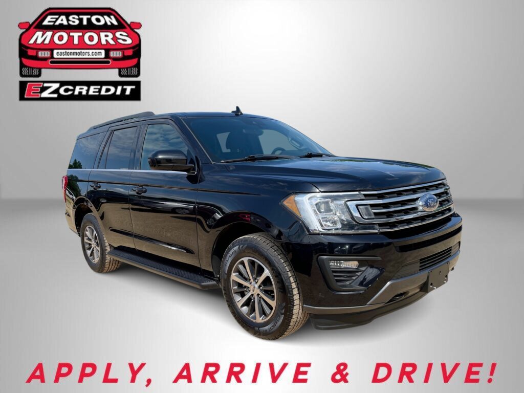 Black Ford SUV featured in a dealership promo with EZCredit logo on a gray backdrop and the words 'APPLY, ARRIVE & DRIVE!' in red.