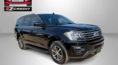 Black Ford SUV featured in a dealership promo with EZCredit logo on a gray backdrop and the words 'APPLY, ARRIVE & DRIVE!' in red.