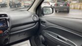 Interior of a car with the dashboard and passenger door visible, looking out at a wet dealership lot with several SUVs parked outside under cloudy skies.