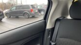 View from the back seat of a car looking out at a parking lot with gray SUVs parked outside the window.