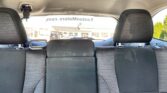 View from the back seat of a car showing the rear benches, headrests, and seat belts with a storefront visible through the rear window.