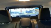 View from the car's rear seats: back of the center console, headrests, and rear window showing a street scene outside.