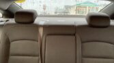 Backseat view of a car interior on a rainy day, looking out the rear window at a storefront with a green awning and parking lot signage outside.