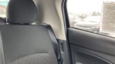 Rear car passenger seat with headrest, dark upholstery, and rain-streaked window with a document sticker on the glass to the right