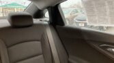 Backseat of a car with a gray fabric seat, seatbelt, and rain-streaked window; a newspaper is taped to the right-side window outside.