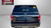 Rear view of a blue Ford Expedition with an Easton Motors logo and EastonMotors.com sticker on the window; visible promotional text 'APPLY, ARRIVE & DRIVE!' at bottom.
