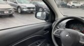 View from the driver's seat showing the steering wheel and side window with a line of cars in a dealership lot outside.