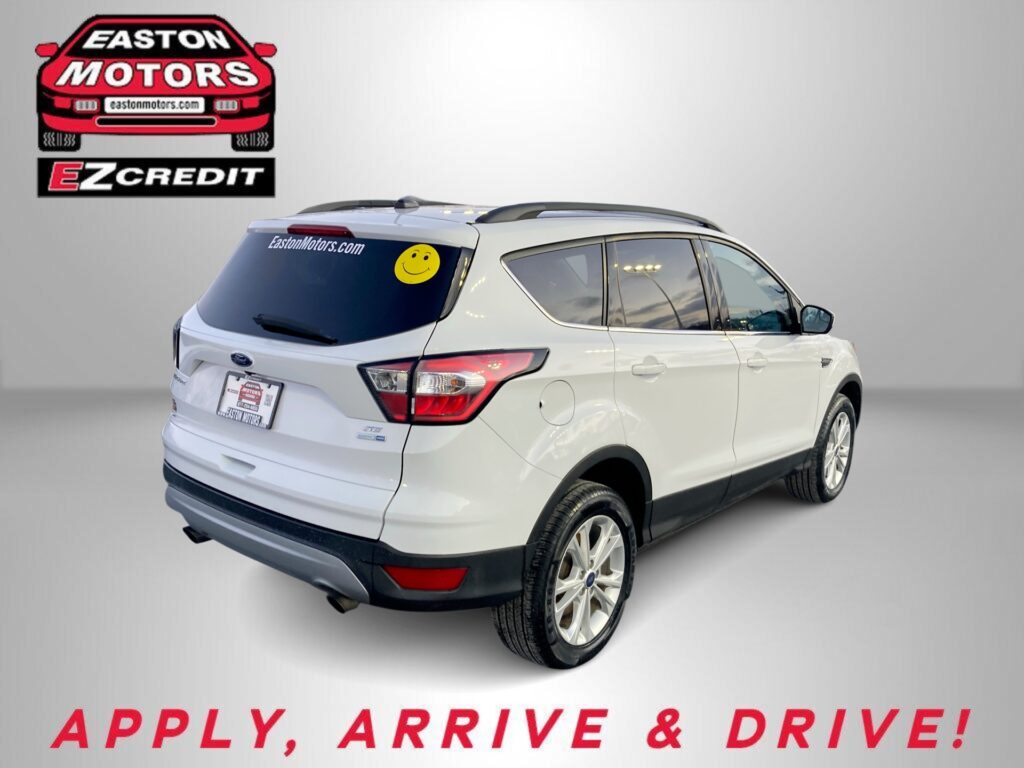 White SUV in a dealership studio with EZCredit logo on the wall and 'Apply, Arrive & Drive' text below the image.