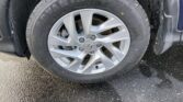 Close-up of a car wheel with a silver alloy rim and tire, resting on wet asphalt, Honda center cap visible