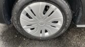 Close-up of a car tire mounted on a silver alloy wheel on wet pavement.