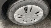 Close-up of a car tire mounted on a silver wheel, wet with scattered water droplets on dark pavement.