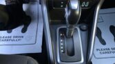 Center console of a car showing the automatic gear shifter, 12V outlet, and climate controls above. Buttery? (Note: keep concise)