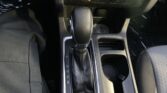 Center console of a car showing automatic gear shifter in Park, with cup holders nearby and storage compartments nearby.