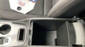 Front car interior: center console with cup holder and an open storage tray; a cardboard box rests on the front passenger seat diagonally.