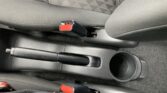 Red seat belt buckle on the center console between the front seats, appearing unfastened in a car interior
