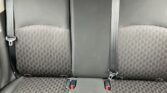 Backseat of a car with three seats, patterned upholstery, and visible seat belts.