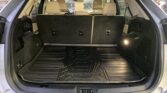 Open SUV cargo area with third-row seats upright, beige interior, and a ridged rubber cargo mat in the boot area of the SUV.