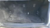 Open car trunk with black carpeting, showing folded floor mats and side hooks along the cargo area walls