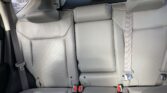 Rear car seats in light gray leather with headrests and seat belts visible, viewed from the trunk area.
