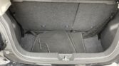 Open trunk showing folded rear seats with dark carpet and a set of floor mats laid out in the cargo area, with a net on the right side.