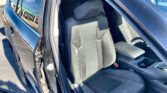 Open car interior showing black fabric seats, front seats with headrests, and a center console/armrest visible with door ajar.
