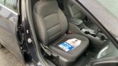 Front passenger seat visible in a wet car, with a blue pamphlet resting on the seat cushion near the center console
