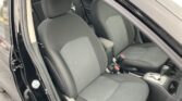 Interior of a car showing front seats and center console, black fabric upholstery, driver and passenger seats visible with seat belts