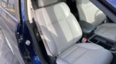 Interior of a blue car showing light gray leather front seats, center console, and seatbelt visible.