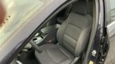 Car interior with the driver’s seat visible, door open, raindrops on windows and roof.