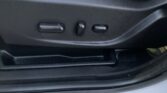 Car seat adjustment panel with two horizontal buttons and a round knob on the side of the seat (vehicle interior).