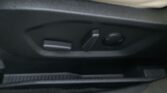Close-up of a car interior door panel showing seat adjustment levers and circular knob in black plastic