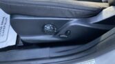 Close-up of the driver's seat side showing adjustment knob and lever, with a tire/load information sticker nearby on the door jamb.