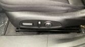 Close-up of a car seat's adjustment controls on the lower side: a rectangular lever, a round knob, and a small toggle Mostly black plastic.