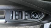 Close-up of a car door control panel with four window switches and a circular side mirror adjustment knob on the armrest area.