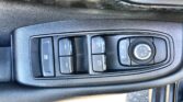 Car door panel showing power window switches and a circular mirror adjustment dial.