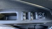 Car door panel with four window switches and a circular mirror control knob on a textured black surface