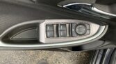 Close-up of a car door interior showing window switch panel and a circular mirror/selector dial with a chrome door handle nearby.