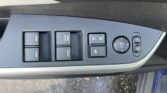 Driver-side power window switch panel with a mirror adjustment knob on a car door panel.
