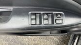 Driver's side car door panel with four window control switches, including an Auto up/down button, and a window/door lock switch; the panel shows signs of wear and scratches.