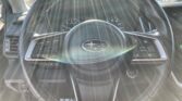 Steering wheel and instrument cluster visible inside a car with sunlight streaming in through the windshield, creating glare in the cabin.