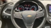 Driver's view of a Chevy steering wheel and dashboard, instrument cluster showing speedometers, with center display at 0 mph and warning icons.