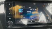 Car stereo touchscreen showing FM 95.7 HD with Roxette's Listen To Your Heart playing, station name and song title visible on screen.