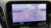 Rearview camera display showing parking lot with orange guiding lines to assist backing up