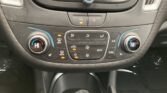 Car climate control panel with dual temperature dials and central button cluster showing seat/defrost and fan icons