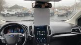 Interior of a Ford SUV showing a large gray sheet hanging from the rearview mirror, partially obscuring the center touchscreen and dashboard.
