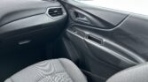 Close-up of a car's front passenger side interior: grey fabric seat, door panel, window, and side mirror visible with an air vent nearby.