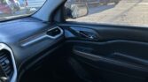 Interior of a car's front passenger side with black dashboard and door panel; side mirror shows a parking lot with several parked cars outside.
