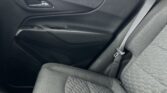 Interior of a car's rear passenger area: dark door panel with chrome door handle, window, and visible seat belt buckle near the seat cushion.