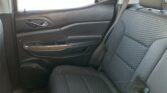 Rear passenger area of a car interior, showing the right-side back seat with textured patterned fabric and a visible seat belt; door panel with chrome door handle is nearby.
