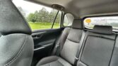 Backseat of a car with gray patterned fabric seats, headrests, and a rear window showing a smiley sticker and a green park outside.